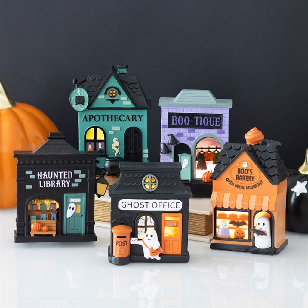 Set of Halloween-themed miniature buildings on a white surface with a dark background.
