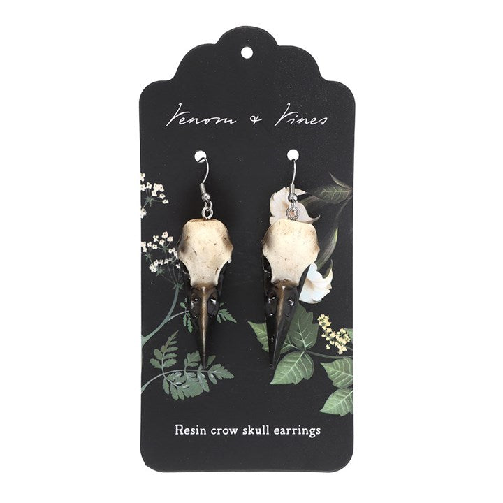 Resin crow skull earrings on a branded card with floral design