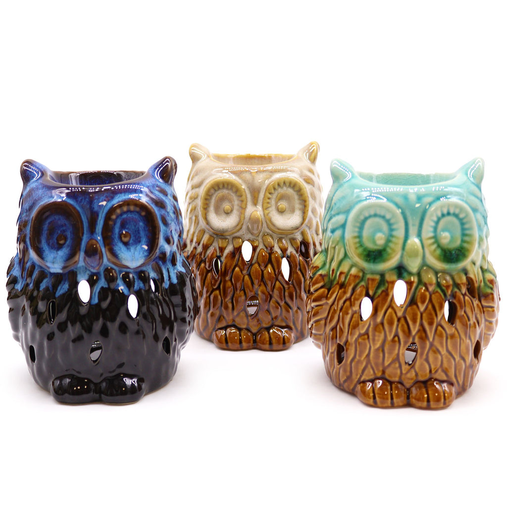 Three ceramic owl-shaped candle holders in blue, brown, and green on a white background