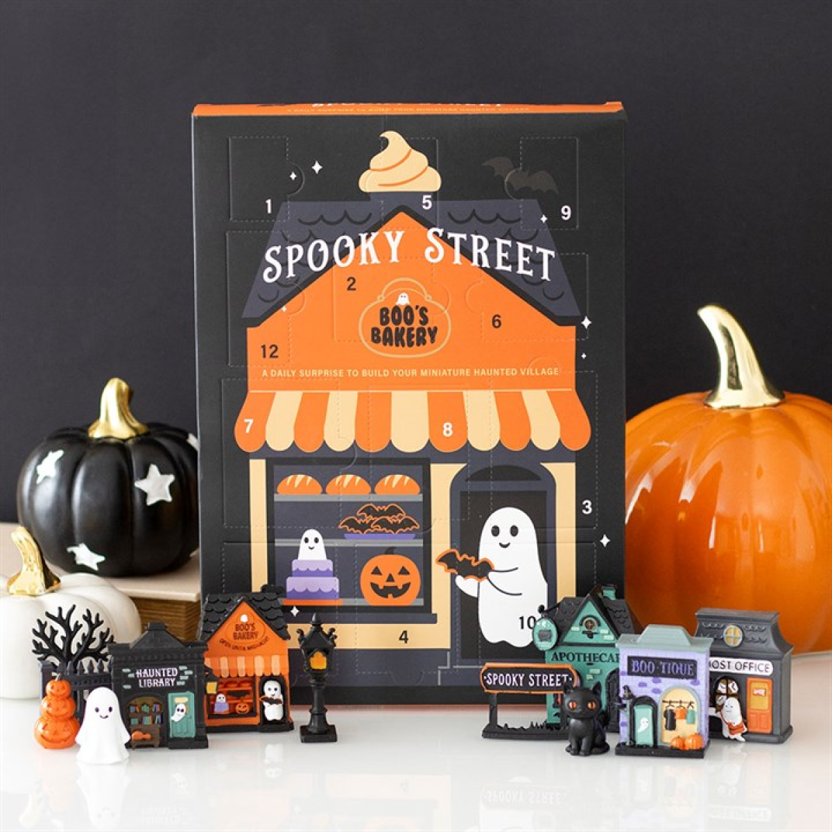 Halloween-themed advent calendar with small buildings and decorations on a black background