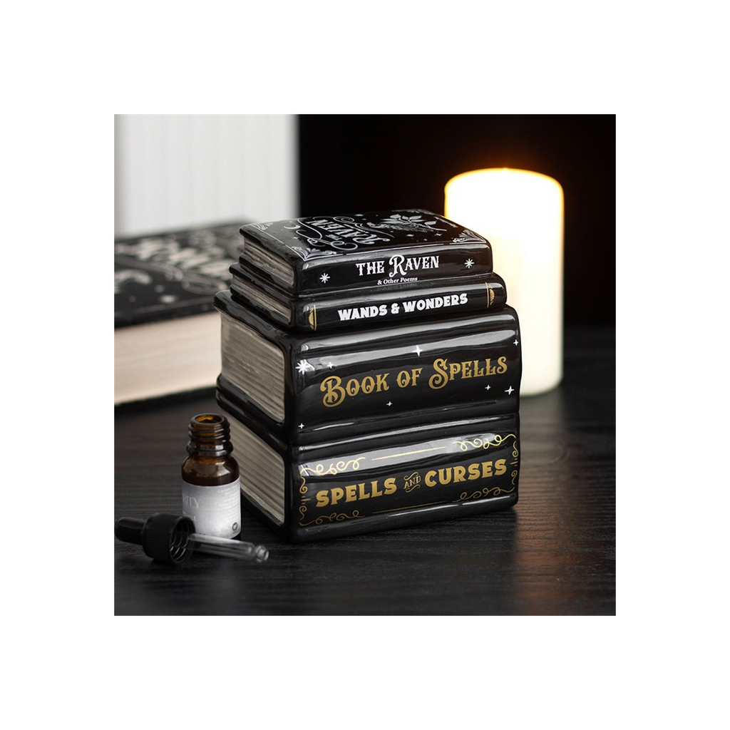 Stack of books titled 'Book of Spells', 'Wands & Wonders', and 'Spells & Curses' on a dark surface with a candle in the background.