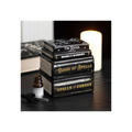 Stack of books titled 'Book of Spells', 'Wands & Wonders', and 'Spells & Curses' on a dark surface with a candle in the background.