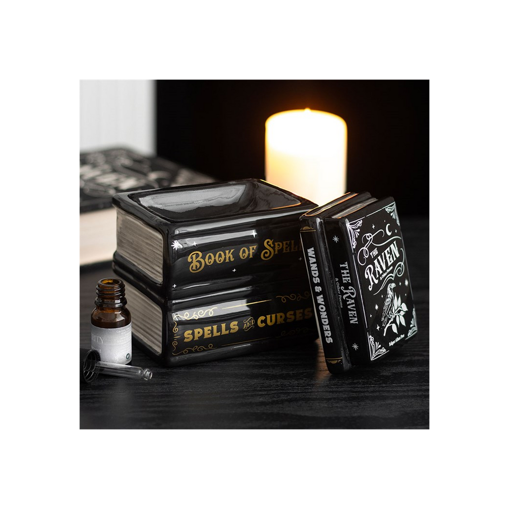 Decorative books with mystical design on a dark surface with a candle in the background