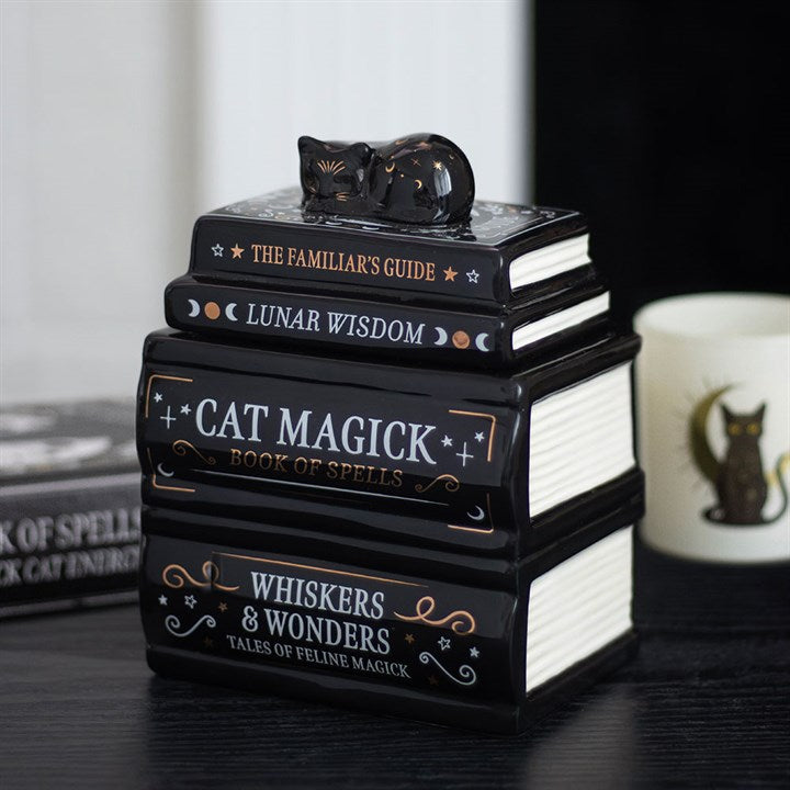 Decorative book stack with a cat figurine on top, themed around cats and magic.