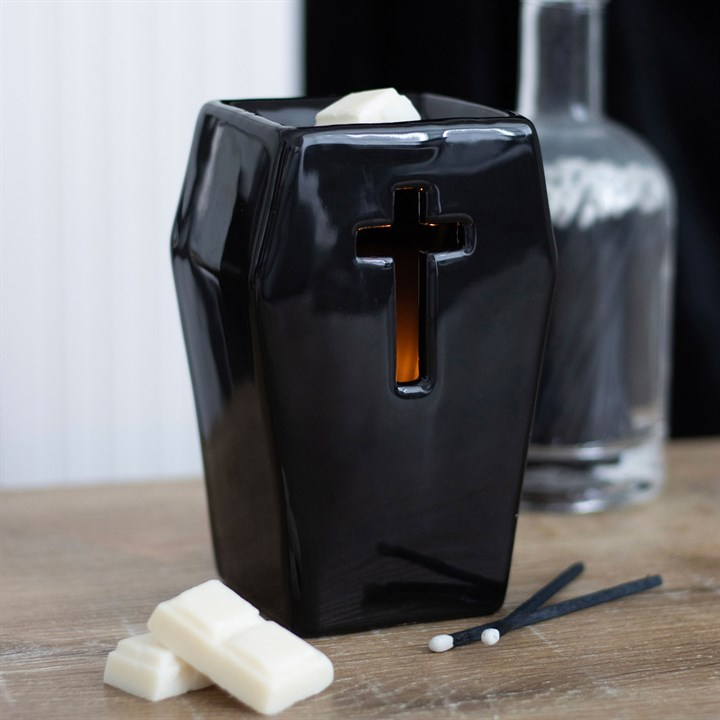 Black candle holder with cross design on a wooden surface