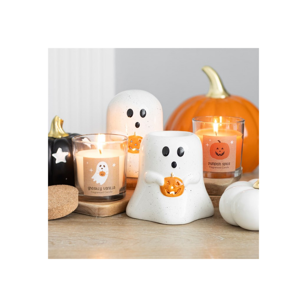 Halloween-themed candles and ghost-shaped containers on a wooden surface.