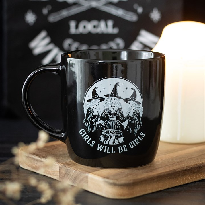 Black mug with a white graphic and text on a wooden surface with a blurred background
