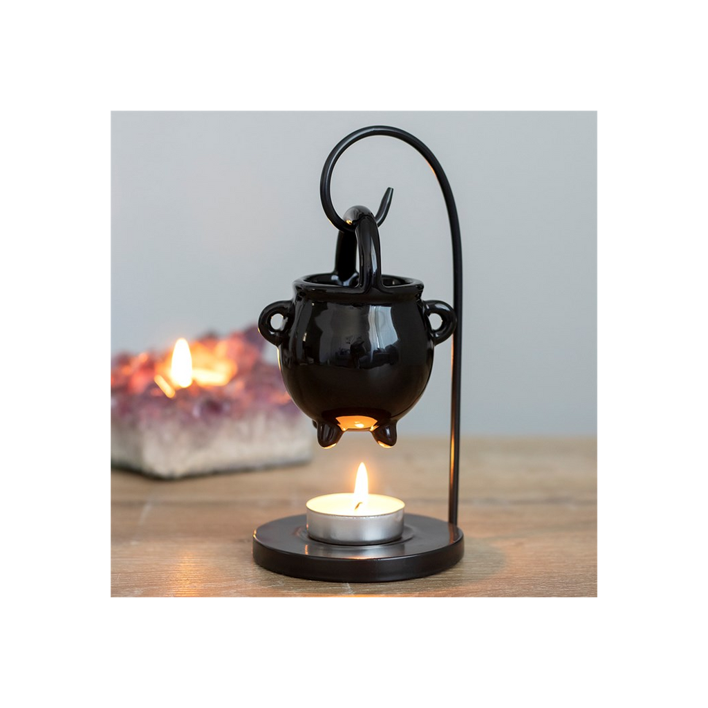 Black metal candle holder with a small candle on a wooden surface.