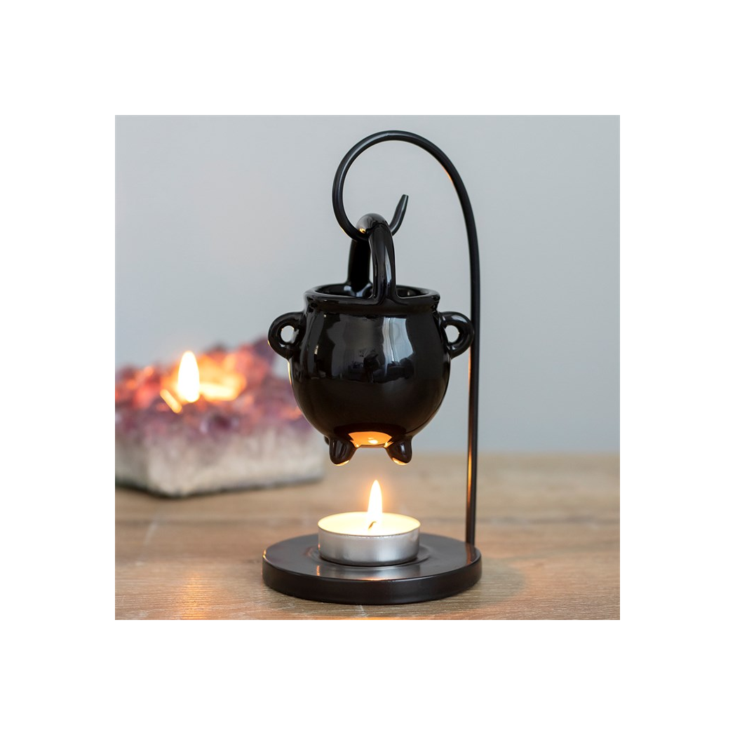 Black metal candle holder with a small candle on a wooden surface.