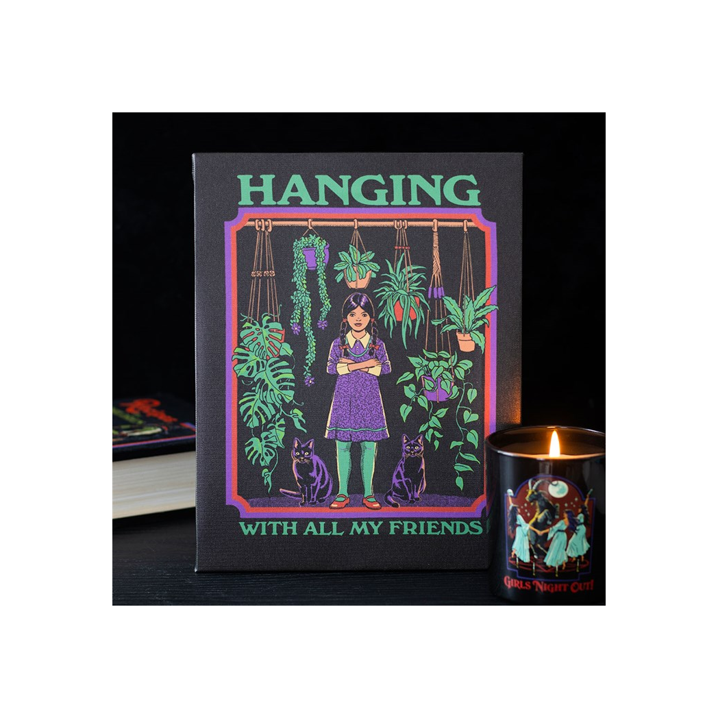 Framed artwork with a person surrounded by plants and cats, titled 'Hanging with All My Friends', next to a lit candle.