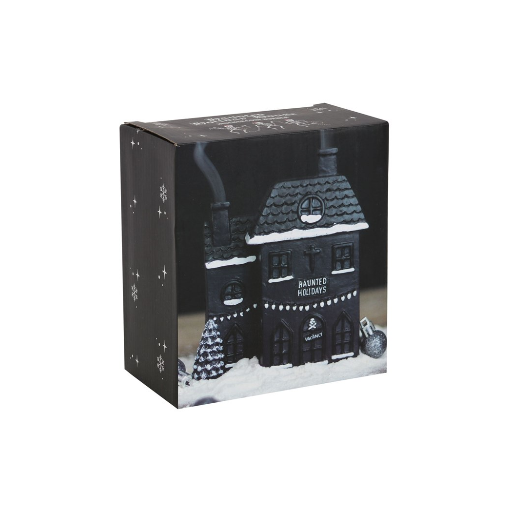 A boxed product featuring a black haunted house illustration with snow and small ornaments, photographed on a plain white background.