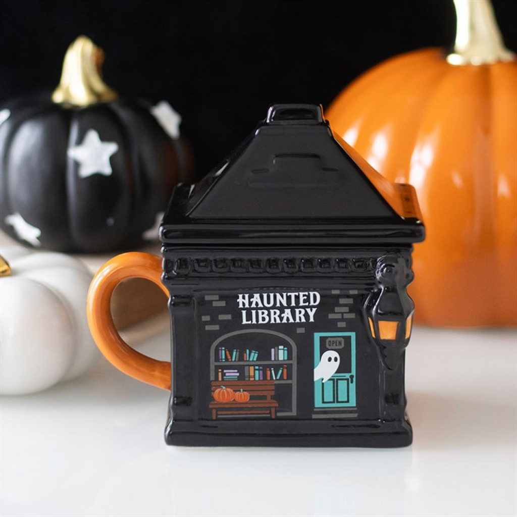 Halloween-themed mug shaped like a haunted library with pumpkins in the background