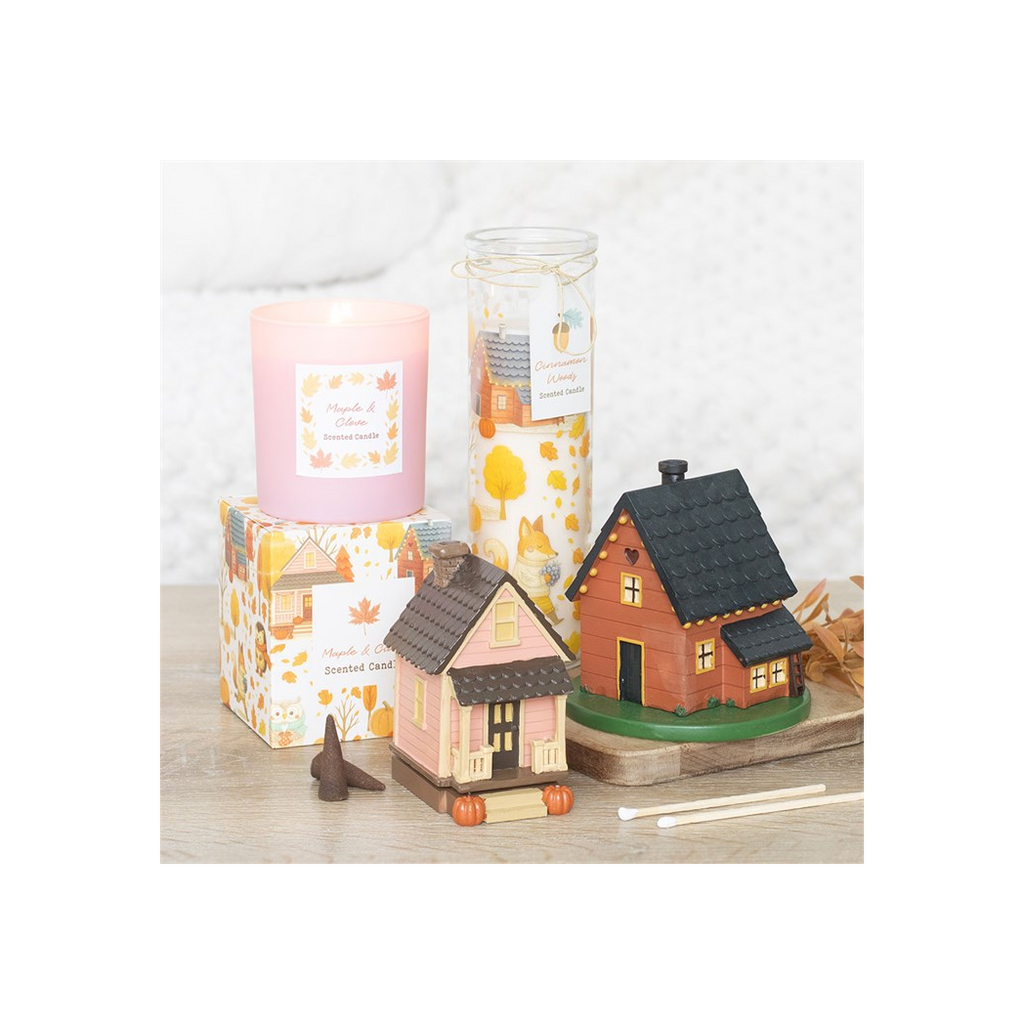 Decorative candles and small houses on a wooden surface with a white background
