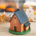 Small wooden house figurine on a round green base with a blurred background