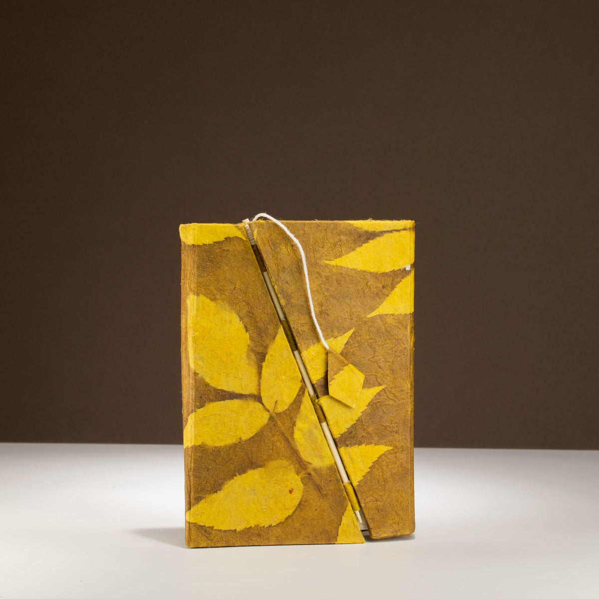 Notebook with yellow leaf pattern on cover against a brown background