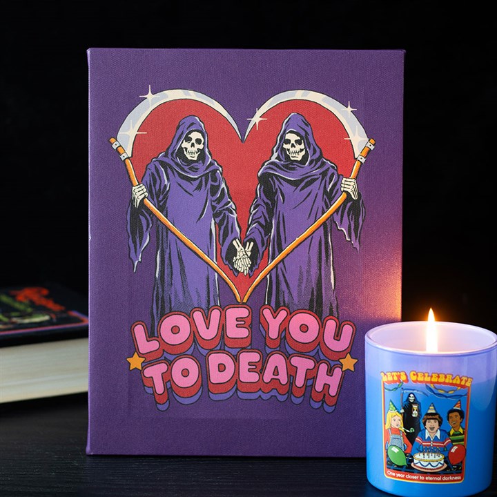 Purple book with Grim Reaper illustration and 'Love You to Death' text, next to a lit candle.