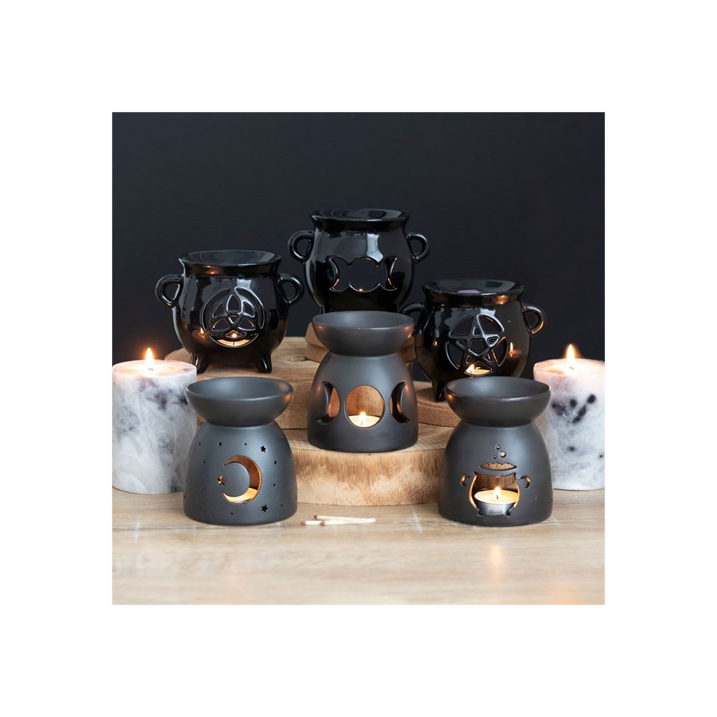 Set of black ceramic oil burners with decorative designs on a wooden surface.