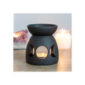 Black ceramic oil burner with cut-out moon phases on a wooden surface.