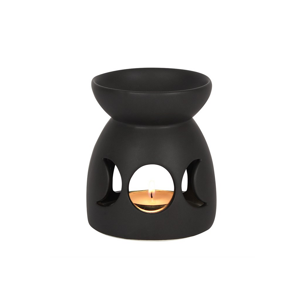 Black wax warmer with a lit candle inside on a white background