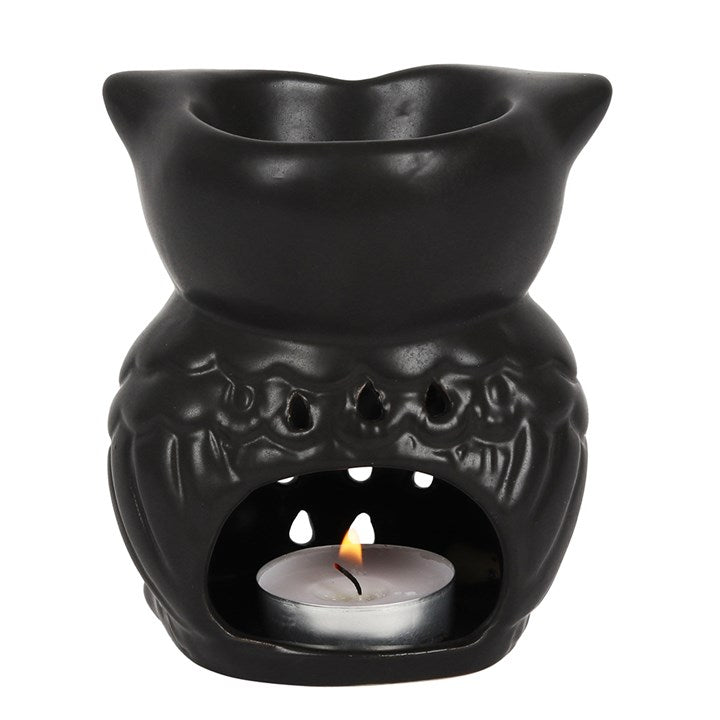 Black ceramic oil burner with a lit tealight candle on a white background