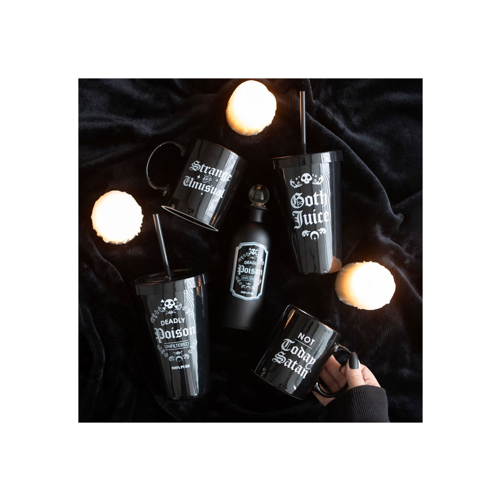 Black mugs and tumblers with gothic-themed designs on a dark fabric background.