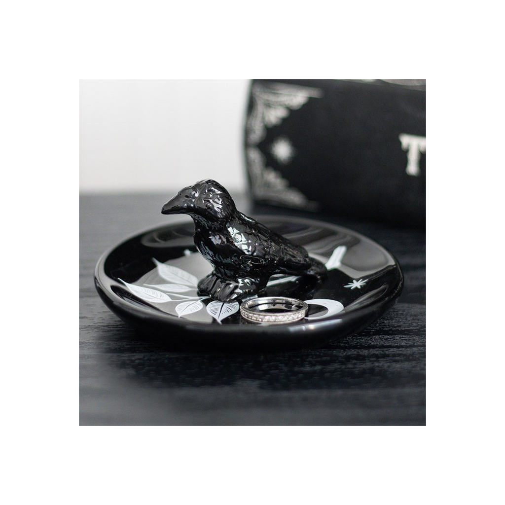 Black bird-shaped ring holder with rings on a dark surface