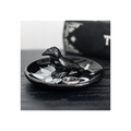 Black bird-shaped ring holder with rings on a dark surface