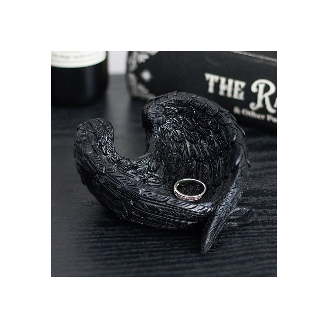 Black decorative angel wing dish with a ring on a dark surface