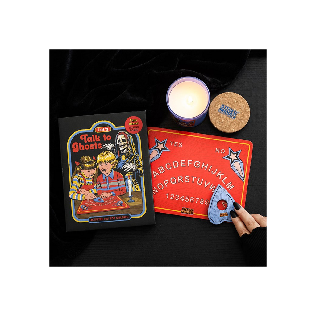 Halloween-themed board game with a candle and coaster on a dark surface