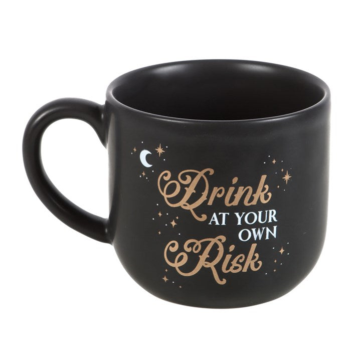 Black mug with gold text 'Drink at your own risk' on a white background
