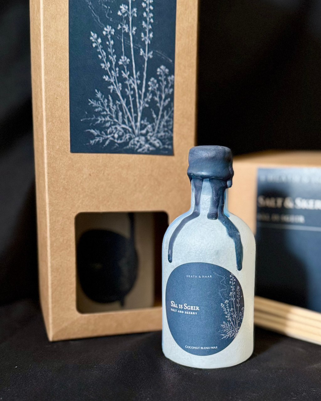 A small frosted glass bottle of South in the Hills 'Salt & Skerry'  blend essential oil, styled in front of its kraft paper packaging box.