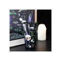 Tumbler with skull and potion design on a dark surface with a candle and book in the background