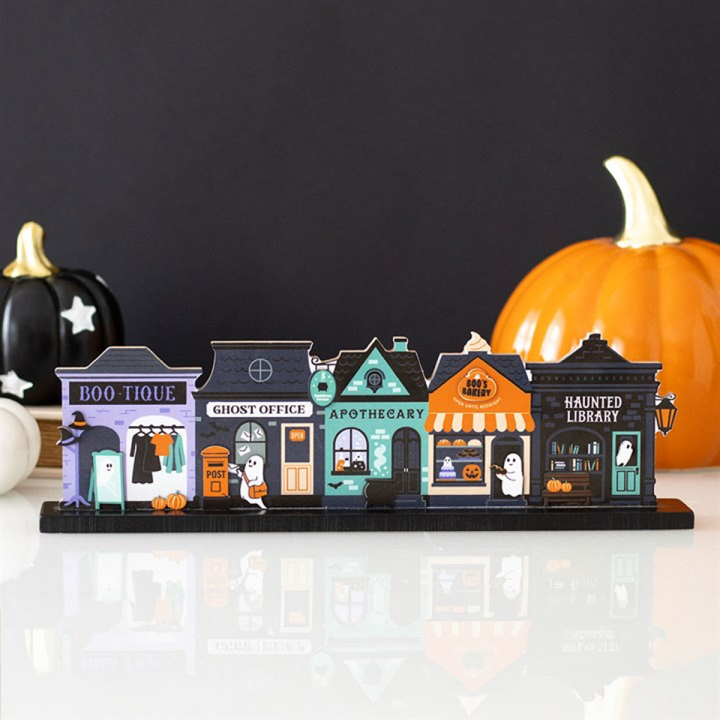 Halloween-themed model town with colorful buildings and pumpkins on a reflective surface.