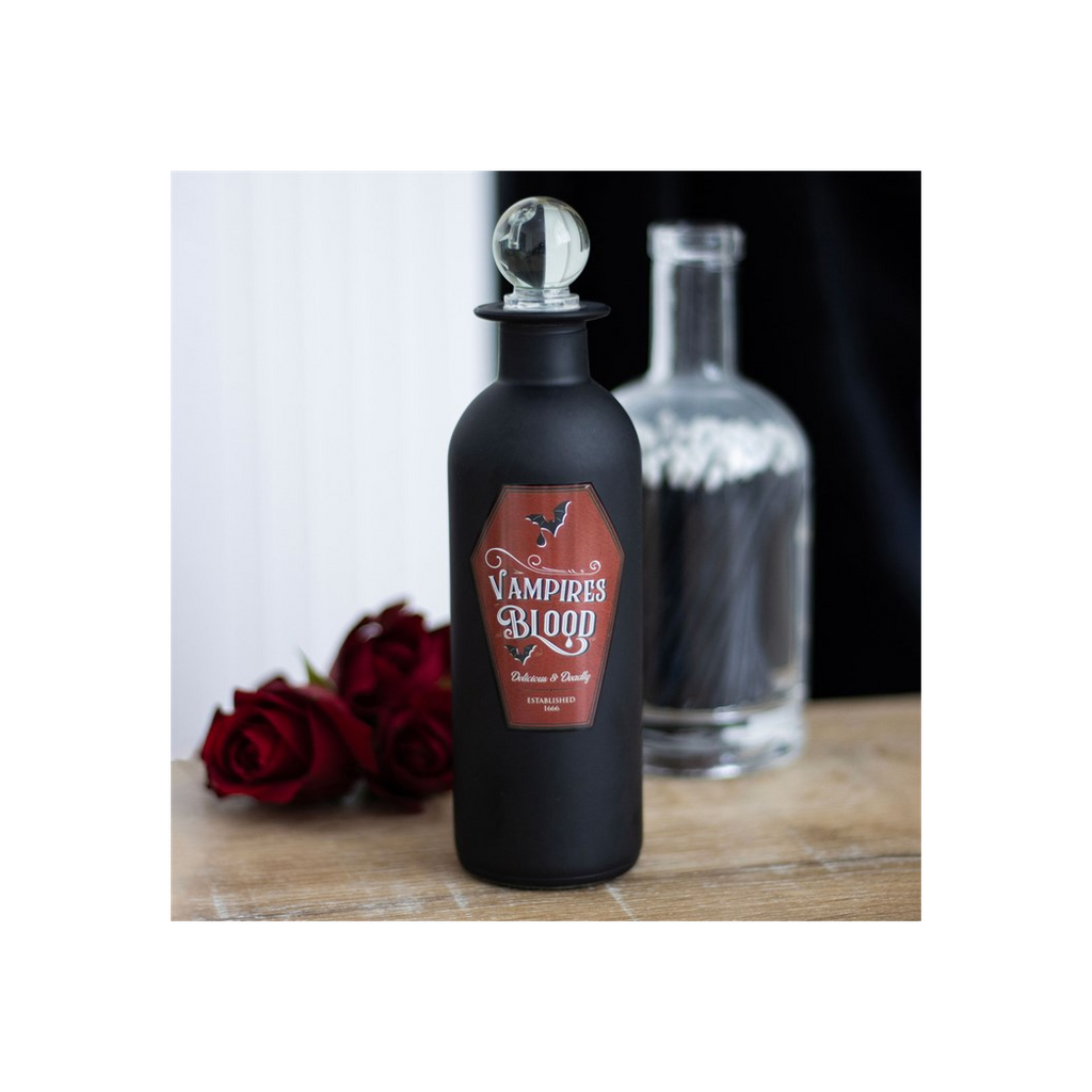 Black bottle labeled 'Vampire's Blood' with red roses on a wooden surface
