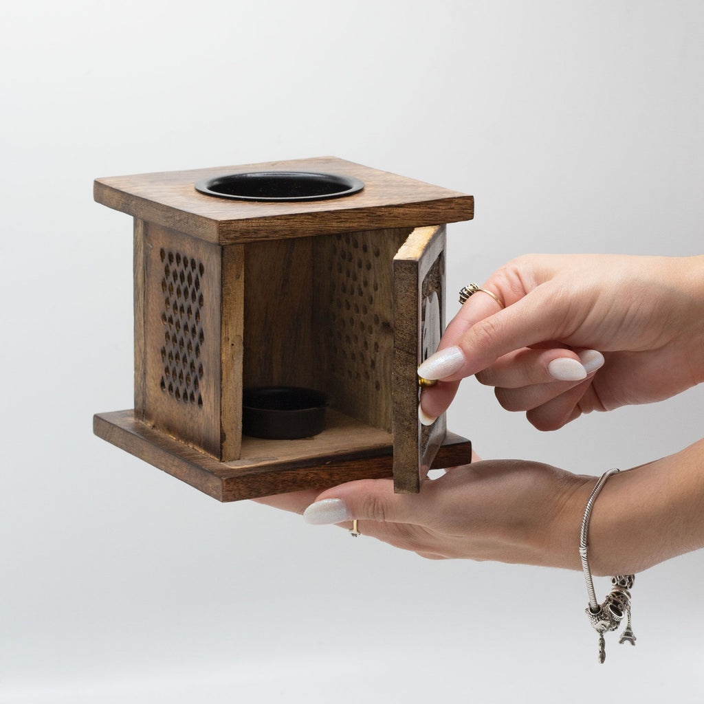Wooden square wax melter with a hand opening it on a light gray background