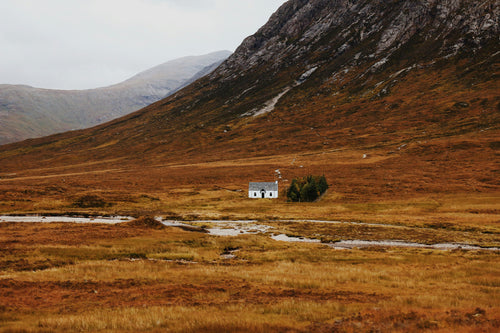 Small white building in a vast, open landscape with mountains in the background
